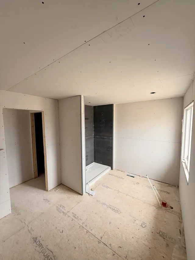A bathroom in a Union West home: walls and closets hung, the shower in dark backer board.