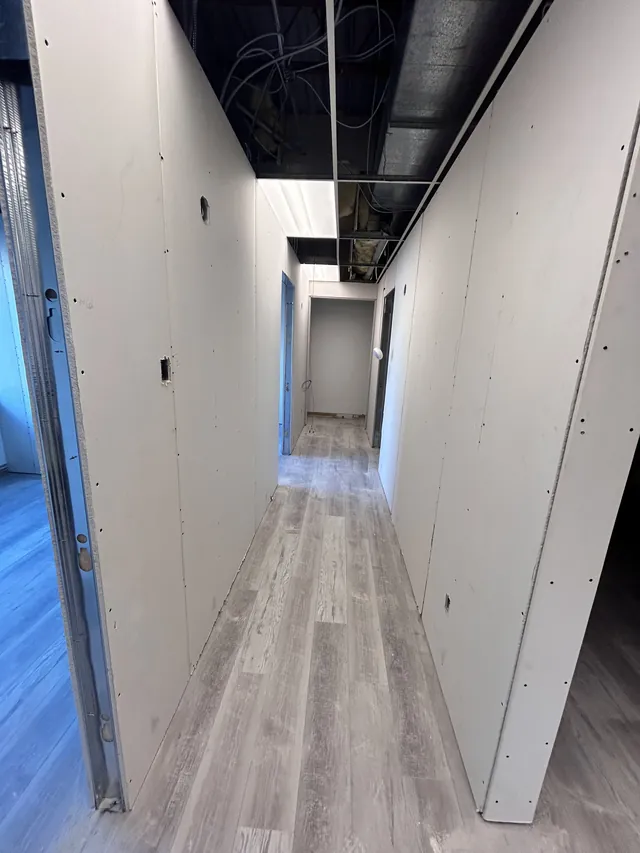 A long hallway with both walls boarded and the ceiling still open above.