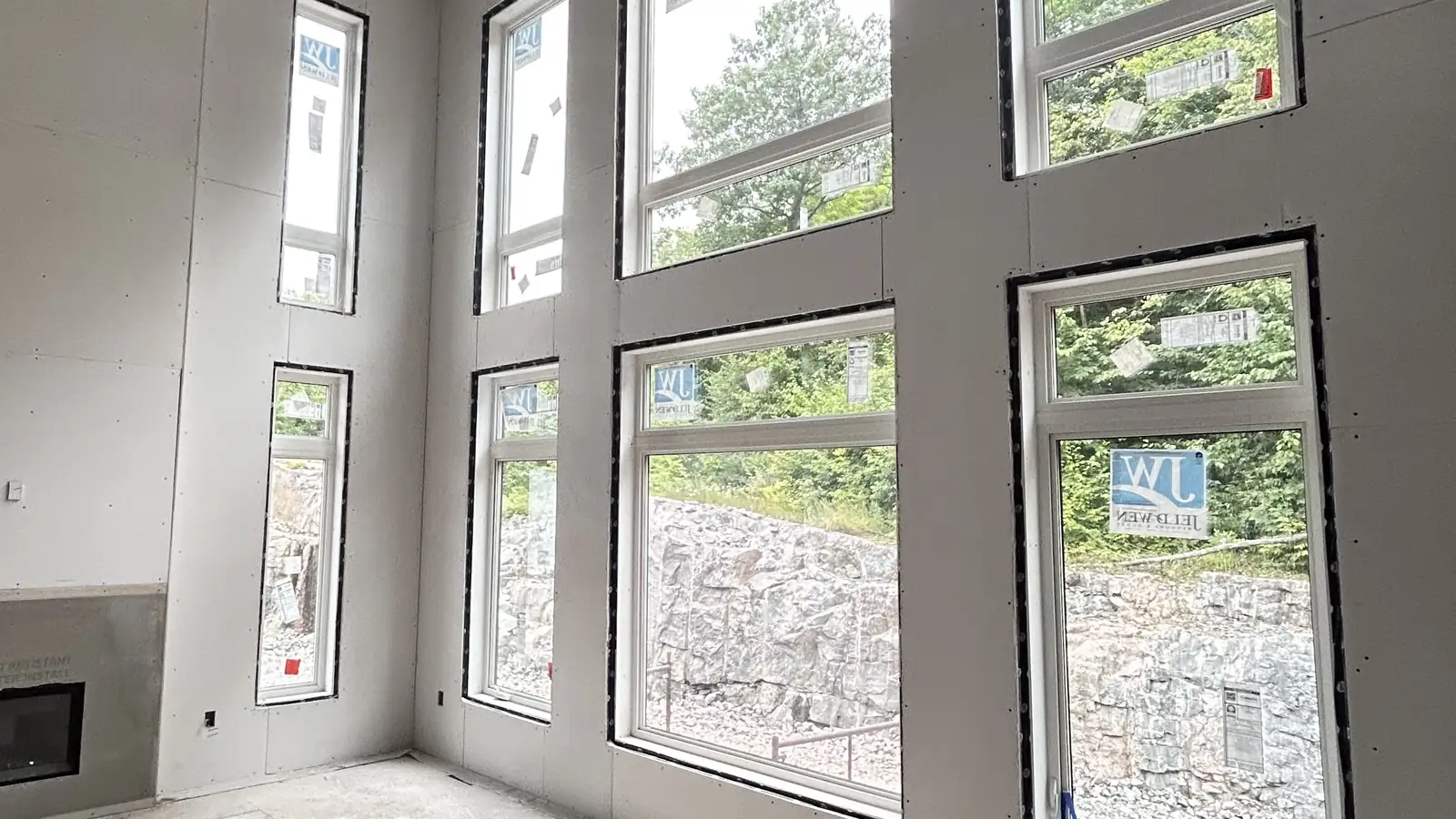 A KOSO job: a tall great room wall of windows, every wall and ceiling hung with drywall.