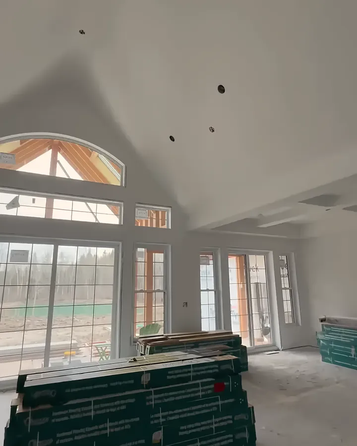 A vaulted great room with a Level 5 finish: smooth walls and ceiling around an arched window.
